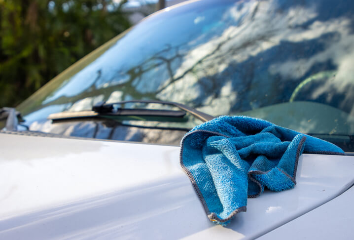 Auto detailer cleaning a vehicle’s windshield in your auto detailing career