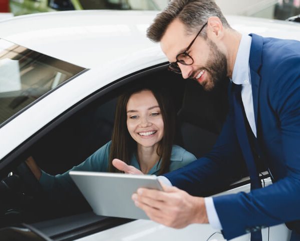 Male car sales professional in conversation with a female customer after automotive sales training