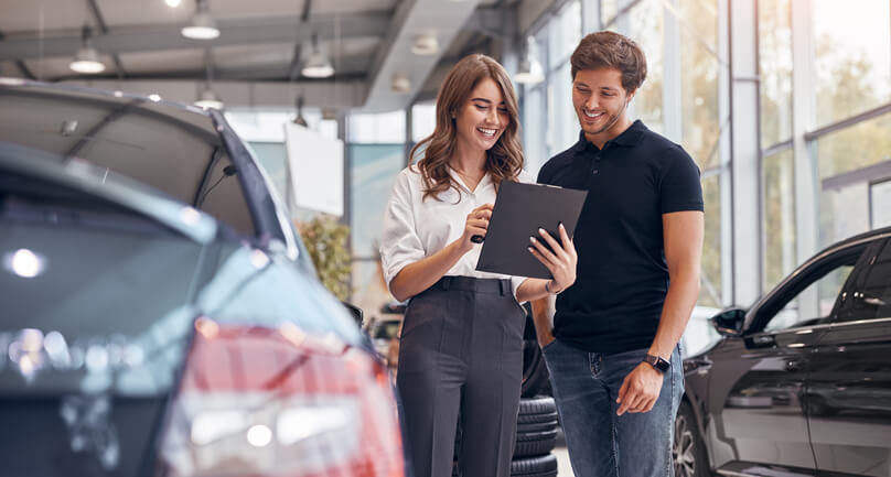 Car sales professional discussing a contract with a client after automotive sales training