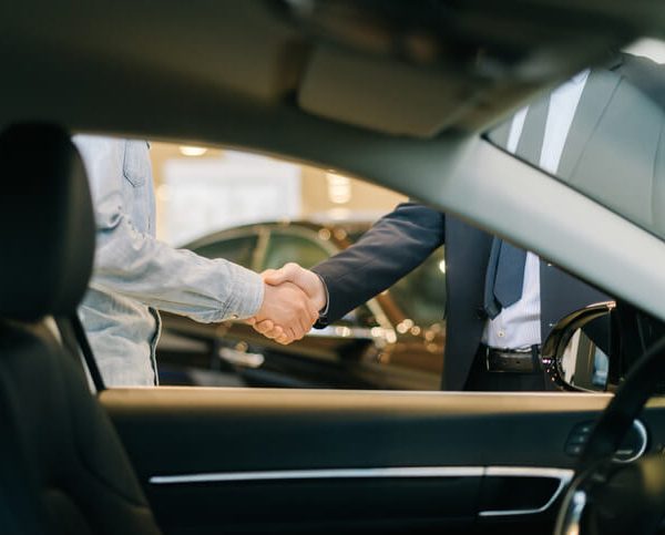 Car salesperson shaking hands with a customer after automotive sales training