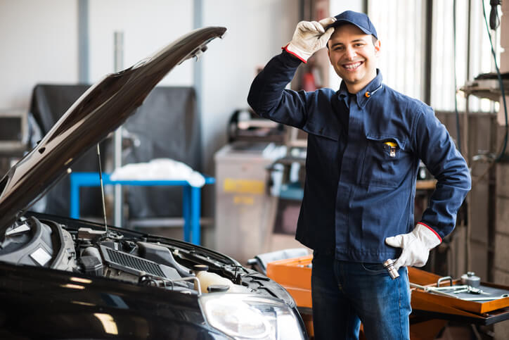 A diesel mechanic smiling in a garage after diesel mechanic training