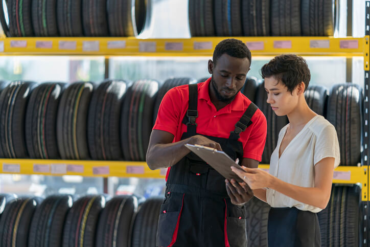  A student in automotive school talking to a female customer in a service centre.