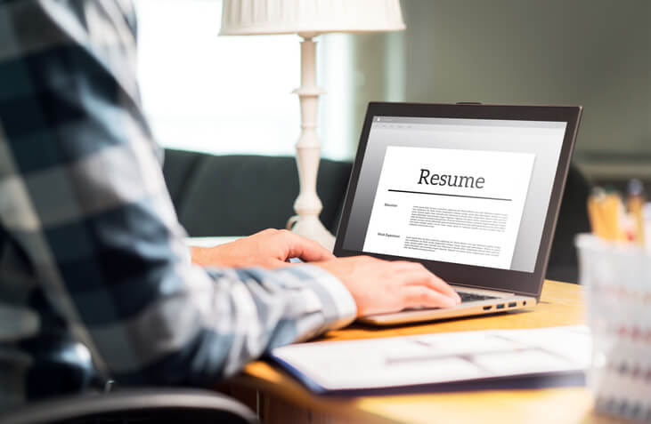 A dispatch training graduate typing a resume on a laptop.