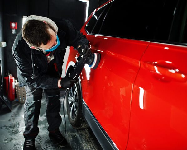 automotive school student buffing a shiny red paint effect on a car