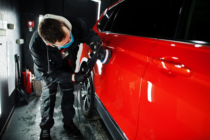 automotive school student buffing a shiny red paint effect on a car