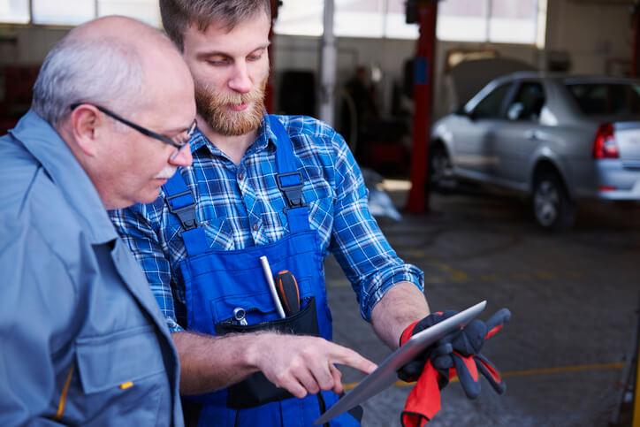 A student in automotive school showing a client more information on a tablet.