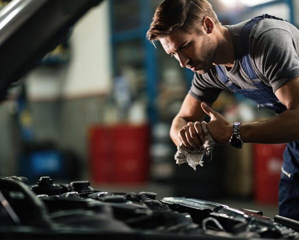 A diesel mechanic training grad working under the hood of an engine in a garage.