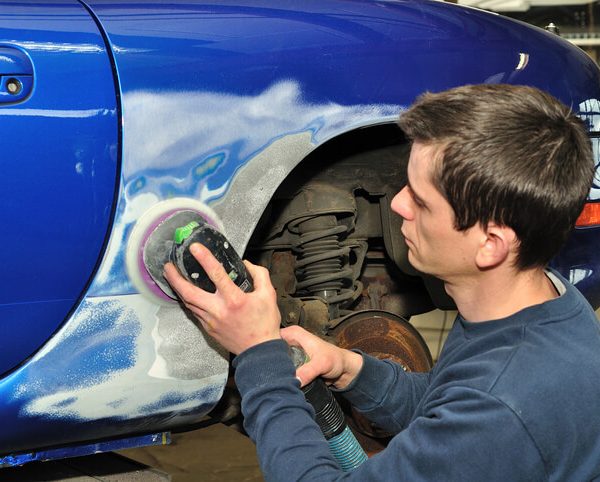 auto body training grads examining a car’s exterior