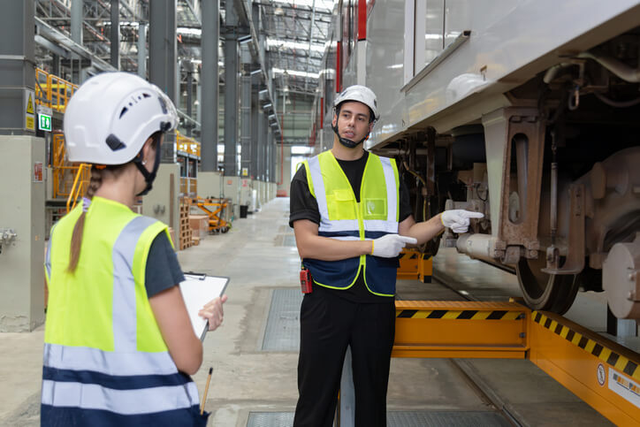 A male locomotive mechanic passing instructions to his colleague