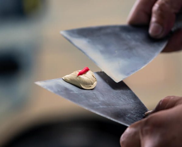 An auto detailing professional using body filler after auto body training