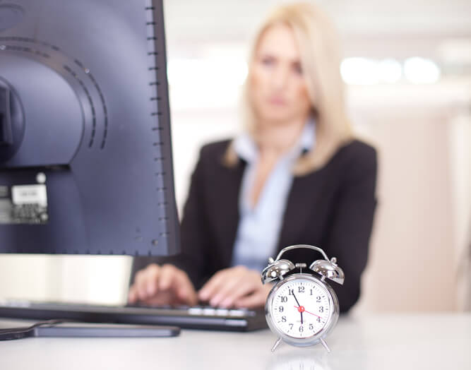 A dispatch training grad working at a desk with a miniature clock next to her