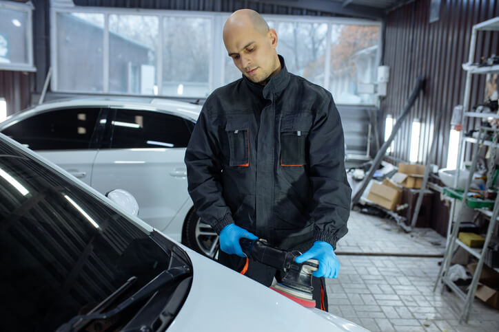 A showroom prep specialist washing a vehicle’s wheels with special detergent after auto detailing training