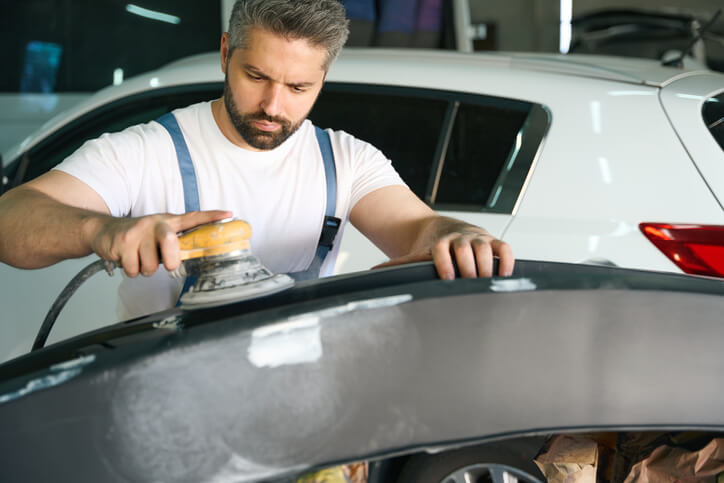 A focused showroom prep specialist polishing the roof of a car after auto detailing training