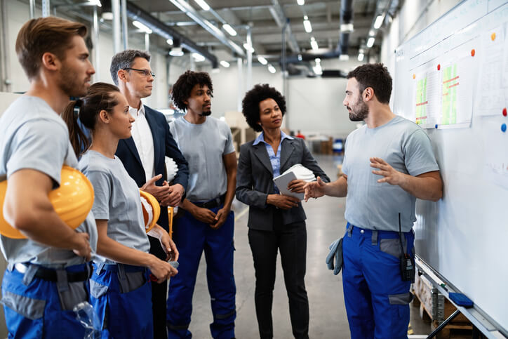 A male warehouse supervisor holding a training session with other warehouse employees after completing his dispatch training