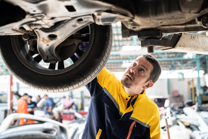 An auto mechanic inspecting the wheels of a vehicle after completing his auto mechanic training