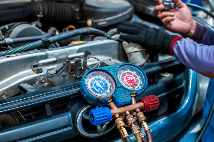 A male climate control specialist working on a vehicle after automotive air conditioning training