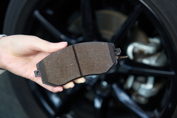 Diesel mechanic holding the brake pad of a race car