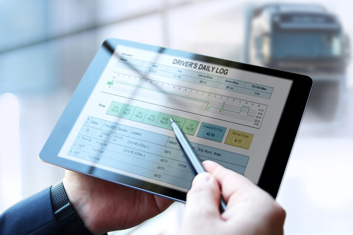 A dispatcher checking the driver’s log software on a tab after dispatch training