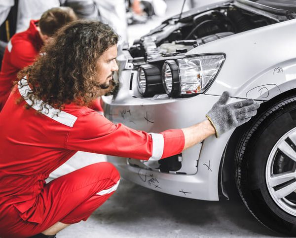 A male auto body technician fixing a damaged car after completing auto body technician training