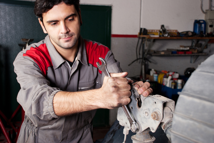 A diesel mechanic training graduate holding a wrench posing in front of a truck