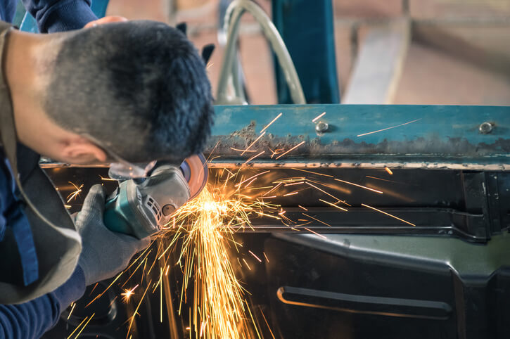 A male mechanic repairing the body of a vintage car after completing auto body technician training