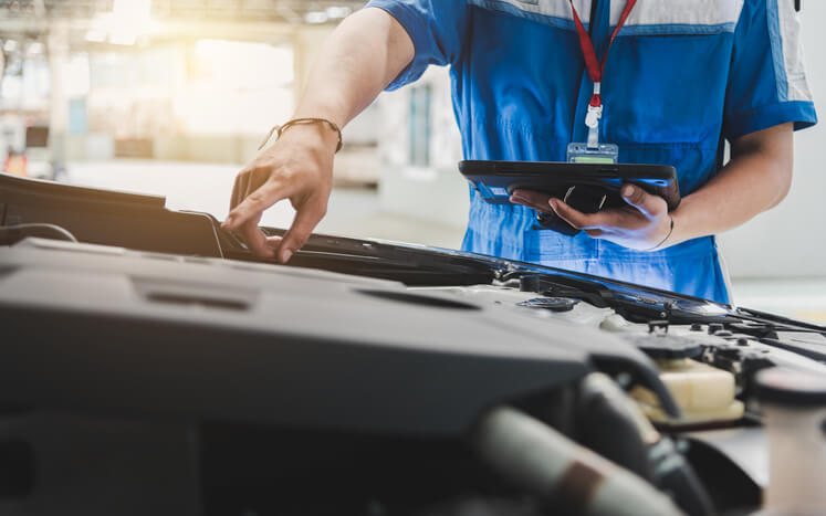 A male mobile auto mechanic diagnosing a vehicle after auto mechanic training