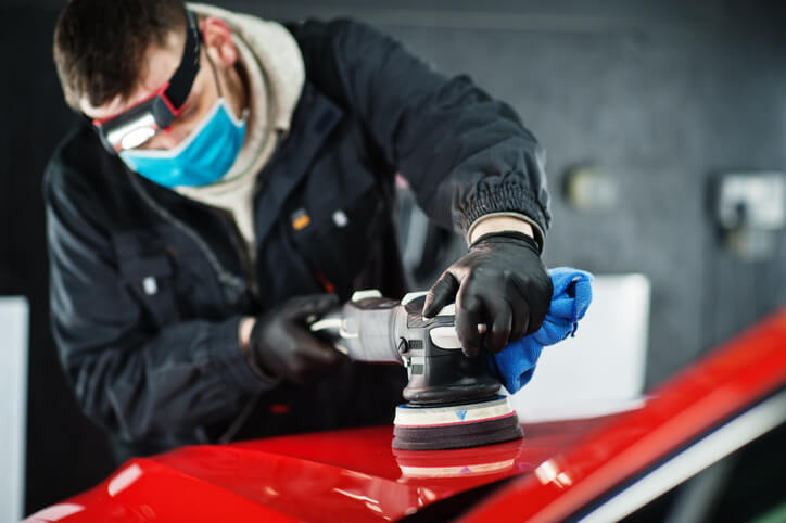 A male auto detailing professional working on a car