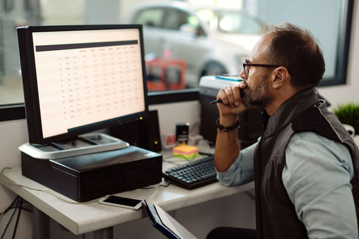 An auto parts training grad working at a computer desk in an auto shop