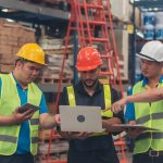 A male dispatcher confirming details with two colleagues at a warehouse after completing his dispatch training