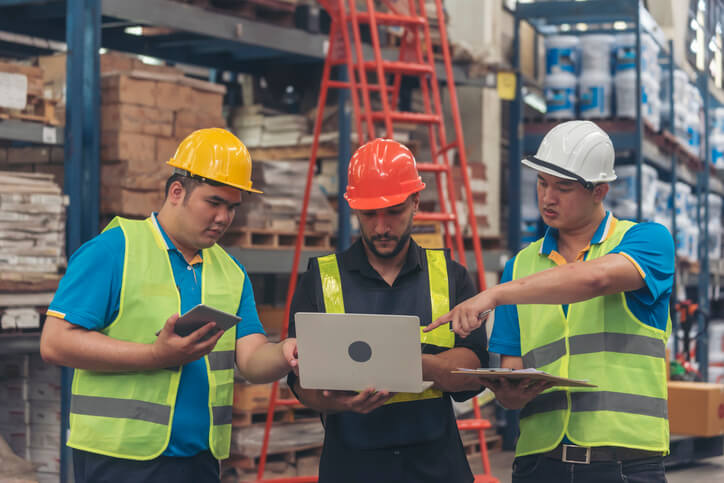 A male dispatcher confirming details with two colleagues at a warehouse after completing his dispatch training