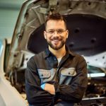 A smiling auto mechanic at an auto body shop