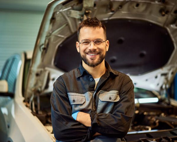 A smiling auto mechanic at an auto body shop