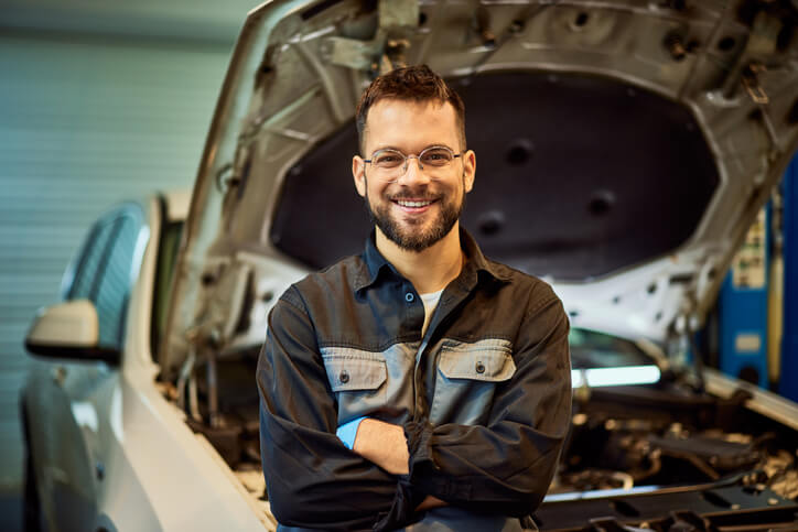 A smiling auto mechanic at an auto body shop