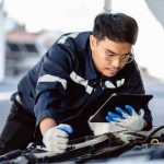 A male auto mechanic working on a luxury vehicle after completing his auto mechanic training