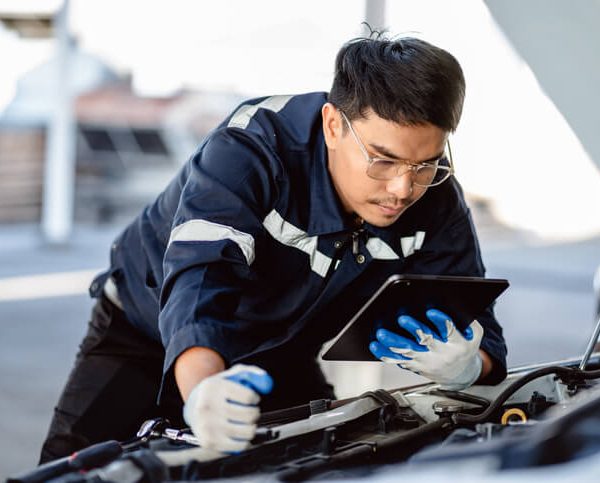 A male auto mechanic working on a luxury vehicle after completing his auto mechanic training