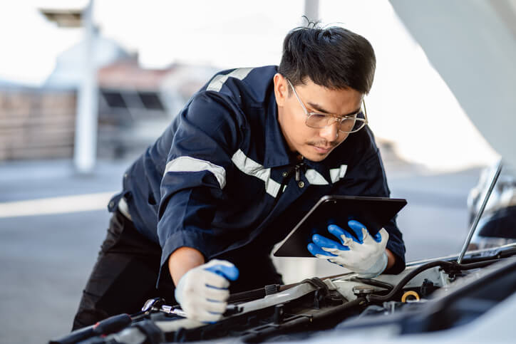 A male auto mechanic working on a luxury vehicle after completing his auto mechanic training