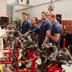 A group of students receiving hands-on auto parts training at CATI