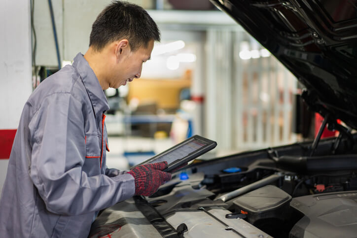 A male auto mechanic using diagnostic software to detect mechanical faults after completing his auto mechanic training