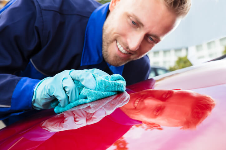 A friendly, focused freelance auto detailer working on a vehicle's exterior after completing his auto detailing training