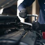 A professional auto mechanic performing maintenance on a car, preparing for a successful future as a shop owner after auto mechanic training.