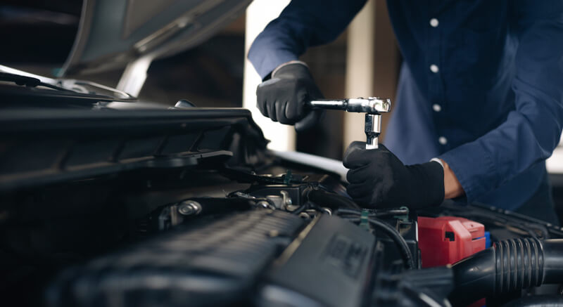 A professional auto mechanic performing maintenance on a car, preparing for a successful future as a shop owner after auto mechanic training.