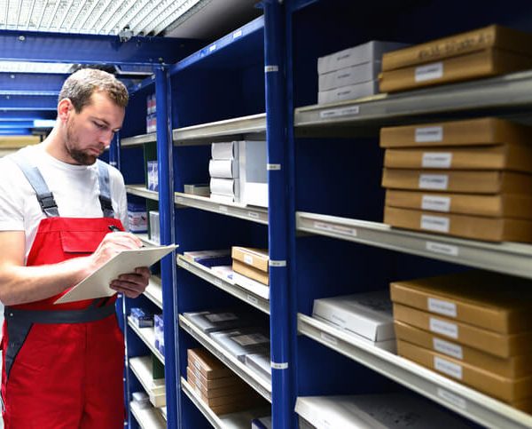 An auto parts specialist reviewing inventory on a tablet in a warehouse after completing his auto parts training.