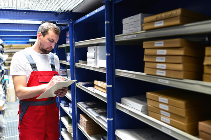 An auto parts specialist reviewing inventory on a tablet in a warehouse after completing his auto parts training.