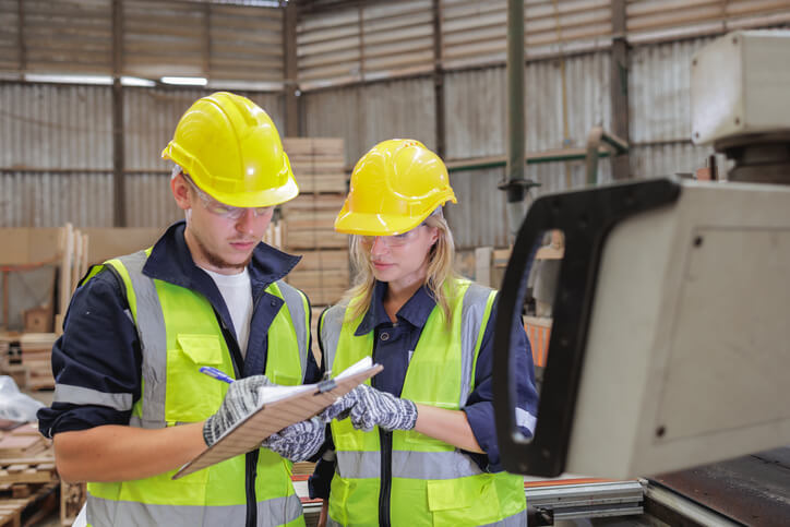 A manager consulting a team member on inventory budgeting in a warehouse after completing his auto parts training.