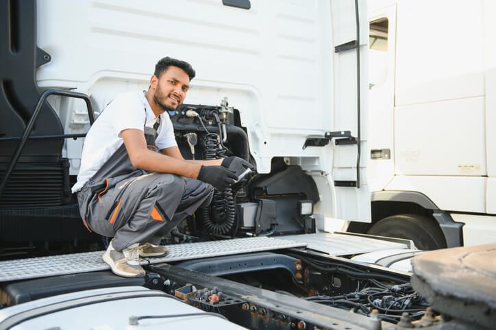 A diesel mechanic training grad sitting on the bed of a large truck